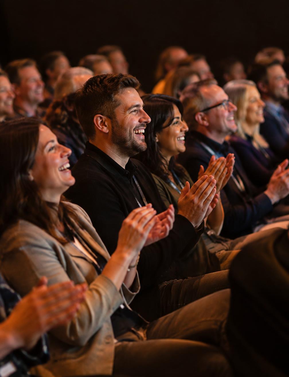 Conference audience laughing and applauding a speaker