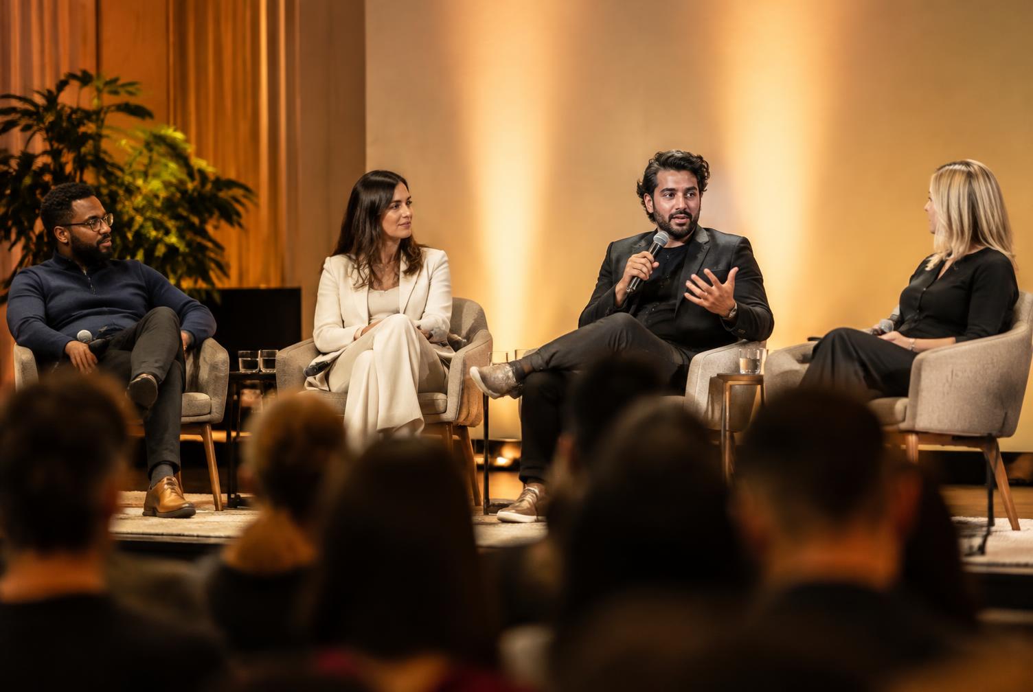Conference panel discussion with a speaker holding a microphone mid-answer